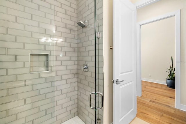 bathroom with hardwood / wood-style flooring and a shower with shower door