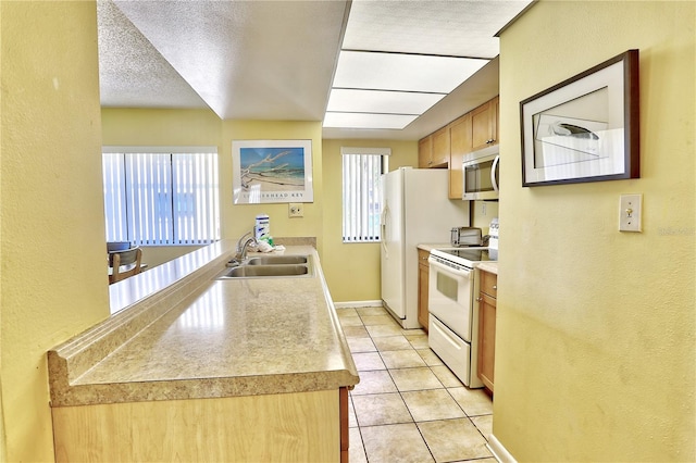 kitchen featuring stainless steel microwave, light tile patterned floors, white range with electric stovetop, plenty of natural light, and a sink