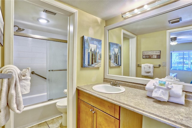 full bathroom featuring combined bath / shower with glass door, vanity, a textured ceiling, tile patterned floors, and toilet