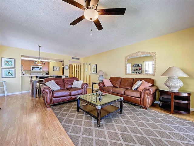 7532 Bayshore Dr Unit 205, Treasure Island, FL 33706 - living area featuring light wood finished floors, a textured ceiling, ceiling fan, and baseboards