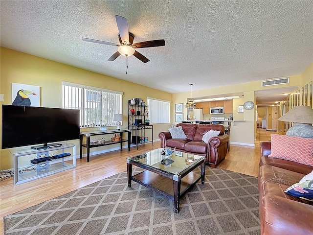 7532 Bayshore Dr Unit 205, Treasure Island, FL 33706 - living room with light wood-style floors, ceiling fan, a textured ceiling, and baseboards