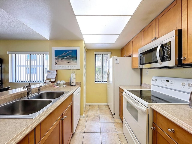7532 Bayshore Dr Unit 205, Treasure Island, FL 33706 - kitchen featuring white appliances, a sink, brown cabinets, baseboards, and light tile patterned flooring