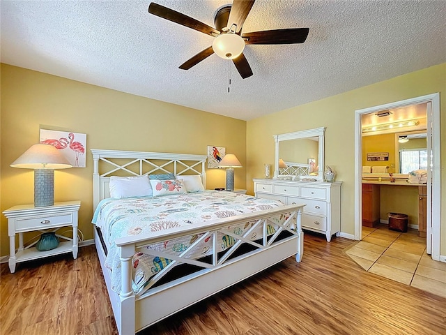 7532 Bayshore Dr Unit 205, Treasure Island, FL 33706 - bedroom featuring light wood-style flooring, a textured ceiling, ceiling fan, ensuite bath, and baseboards