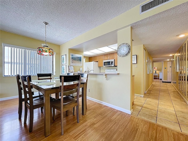 7532 Bayshore Dr Unit 205, Treasure Island, FL 33706 - dining area featuring a textured ceiling, light wood-style flooring, and baseboards