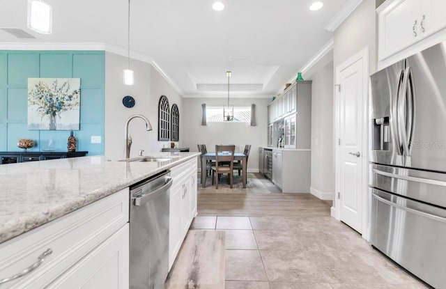 kitchen featuring white cabinetry, appliances with stainless steel finishes, pendant lighting, and a tray ceiling