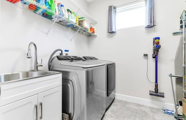 clothes washing area featuring separate washer and dryer, sink, light tile patterned floors, and cabinets