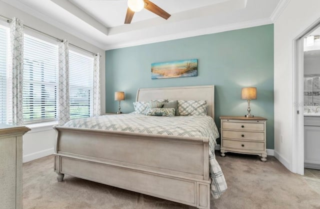 bedroom featuring a tray ceiling, light carpet, ceiling fan, and ensuite bath