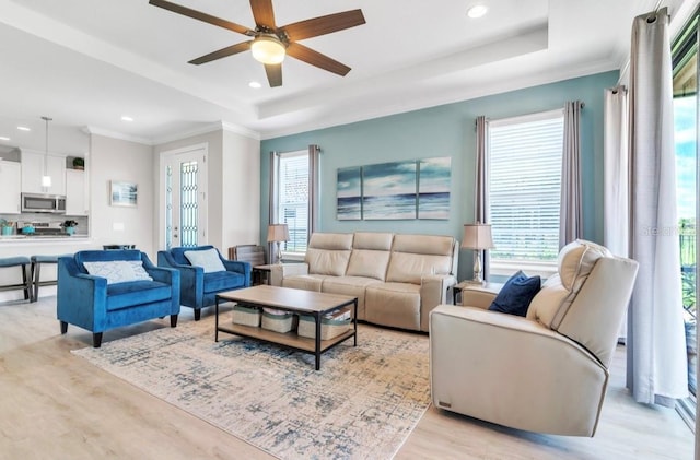 living room with ornamental molding, light hardwood / wood-style floors, a raised ceiling, and ceiling fan