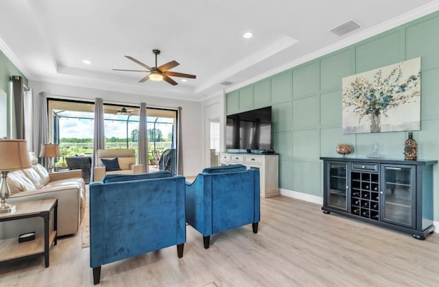 living room with a raised ceiling and light wood-type flooring