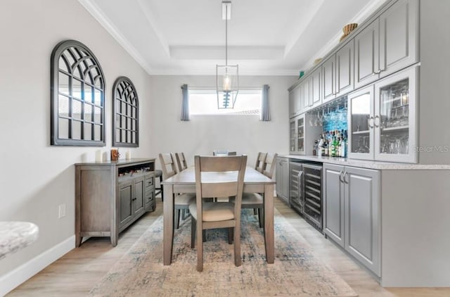 dining space with wine cooler, a tray ceiling, and light hardwood / wood-style floors