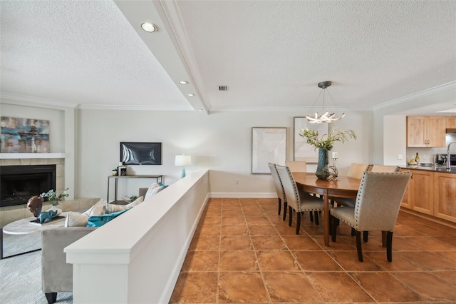 dining area featuring a textured ceiling, a tile fireplace, crown molding, and a chandelier