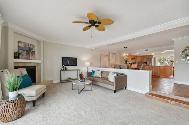 living room featuring crown molding, a textured ceiling, a tile fireplace, light carpet, and ceiling fan