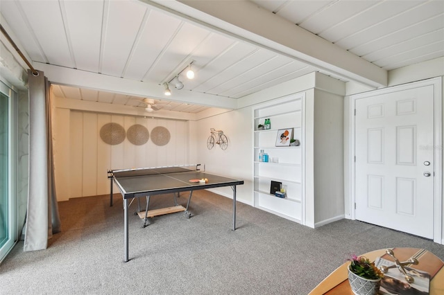 recreation room featuring track lighting, built in shelves, beamed ceiling, and carpet