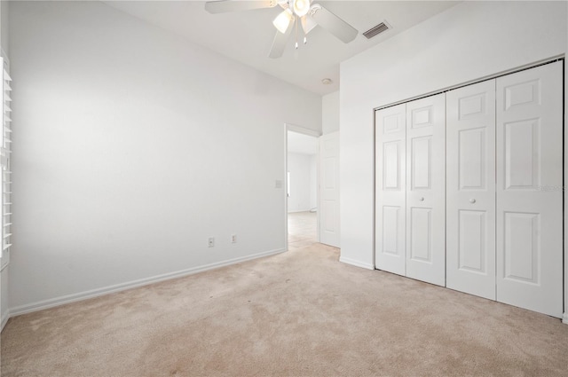 unfurnished bedroom with ceiling fan, light colored carpet, and a closet