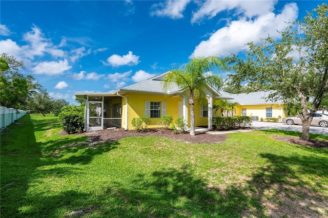 rear view of house featuring a sunroom and a yard