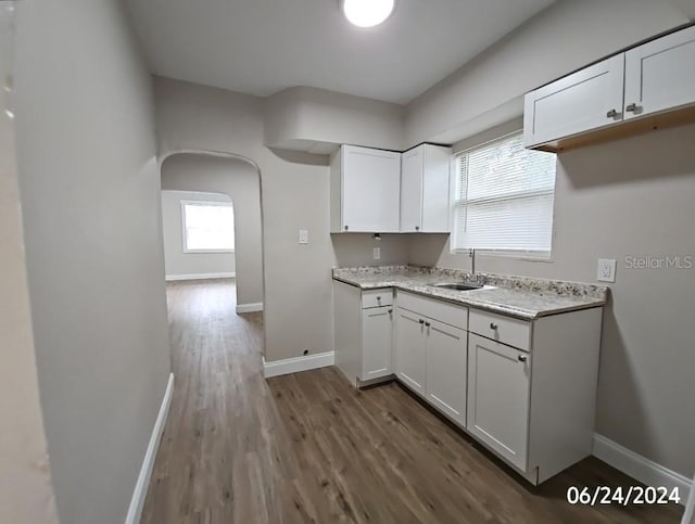 kitchen featuring light stone countertops, dark hardwood / wood-style flooring, white cabinetry, and sink