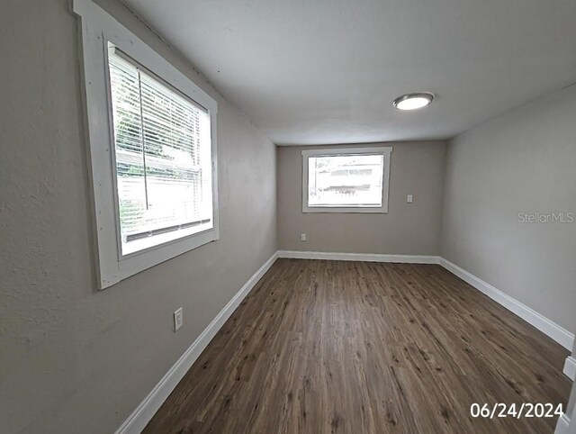 spare room with dark hardwood / wood-style floors and a healthy amount of sunlight