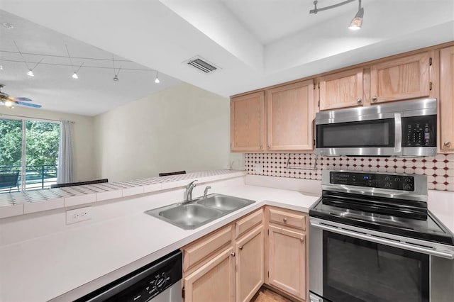 kitchen featuring light brown cabinets, rail lighting, sink, kitchen peninsula, and stainless steel appliances