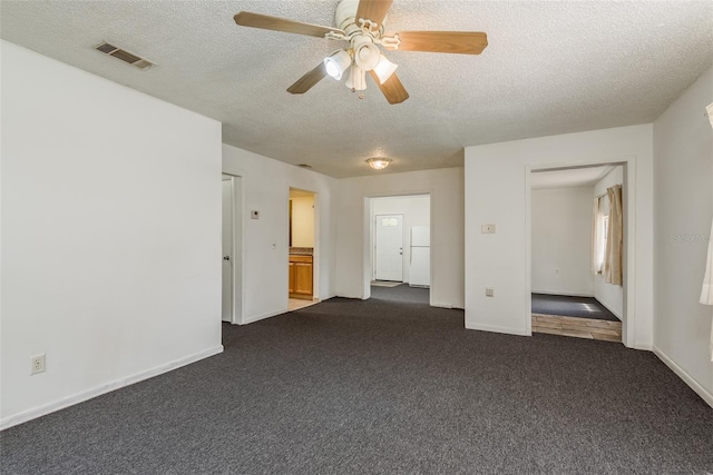 carpeted spare room featuring ceiling fan and a textured ceiling