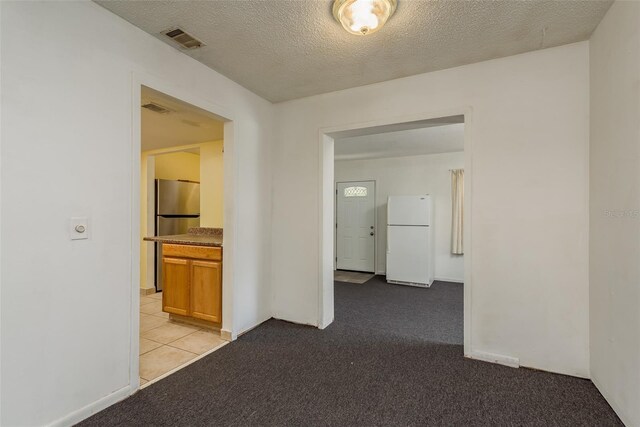 corridor featuring a textured ceiling and light carpet