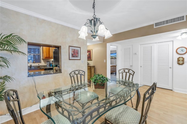 dining area with a chandelier, sink, crown molding, and light hardwood / wood-style flooring