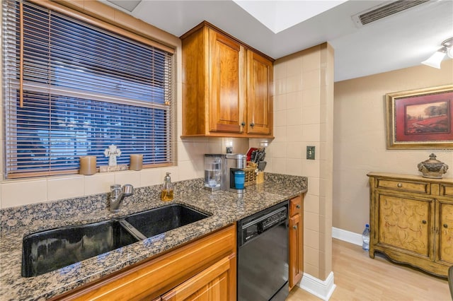 kitchen featuring light wood-type flooring, tasteful backsplash, dark stone counters, sink, and dishwasher