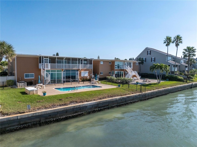 rear view of house featuring a lawn, a sunroom, a balcony, a water view, and a patio