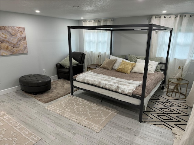 bedroom with a textured ceiling, recessed lighting, wood finished floors, and baseboards