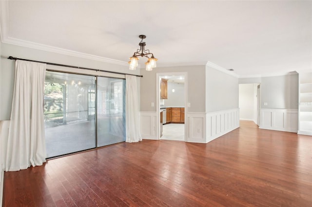 spare room with hardwood / wood-style floors, an inviting chandelier, and crown molding