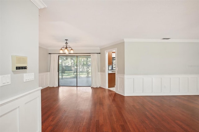 empty room featuring crown molding, dark wood-type flooring, and an inviting chandelier