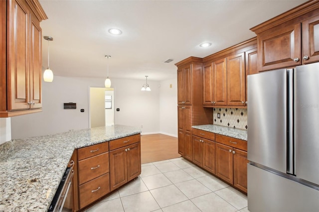 kitchen featuring light stone countertops, pendant lighting, a chandelier, and stainless steel refrigerator