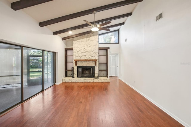 unfurnished living room with high vaulted ceiling, a stone fireplace, hardwood / wood-style flooring, ceiling fan, and beamed ceiling