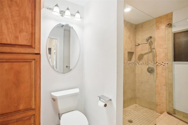 bathroom with a tile shower, tile patterned floors, and toilet