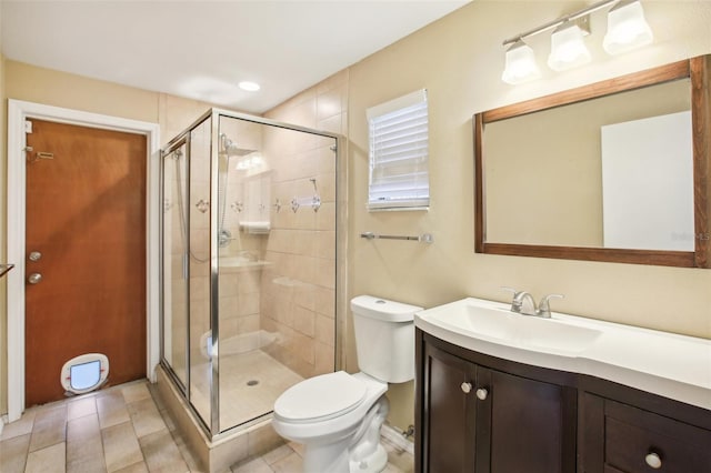 bathroom featuring vanity, toilet, and a shower with door