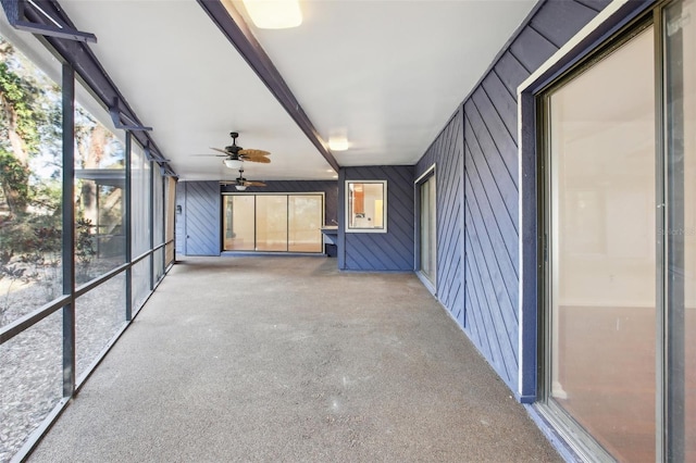 unfurnished sunroom featuring beamed ceiling and ceiling fan