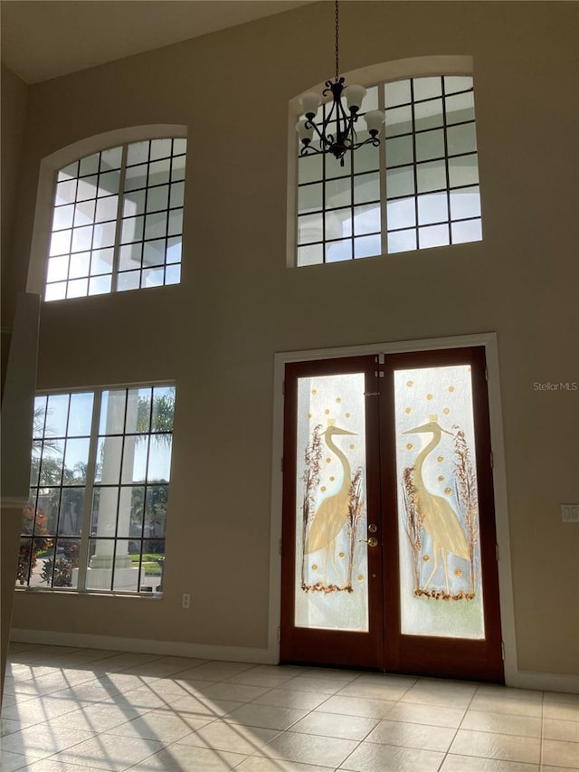 foyer featuring a notable chandelier, plenty of natural light, light tile patterned floors, and french doors