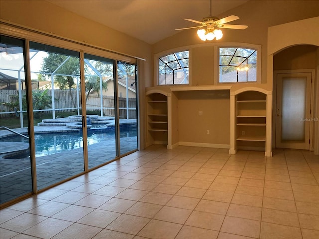 tiled spare room with built in shelves, ceiling fan, and vaulted ceiling