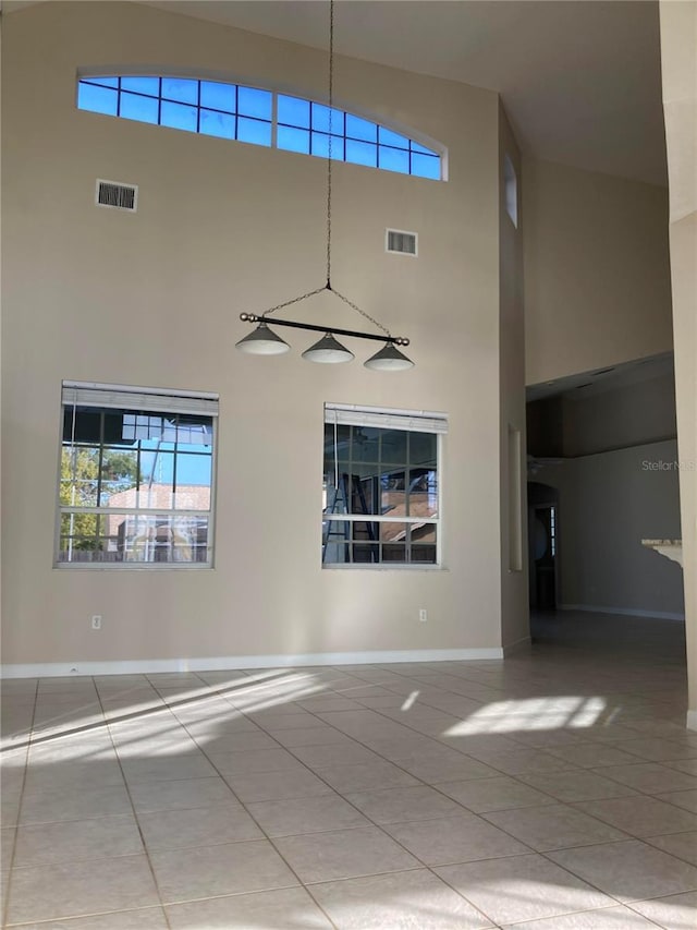 empty room with tile patterned flooring and a towering ceiling