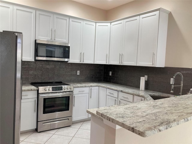 kitchen with white cabinets, sink, decorative backsplash, light tile patterned floors, and stainless steel appliances