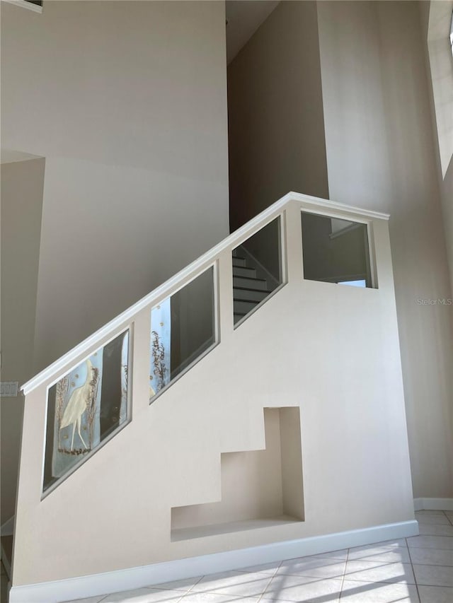 stairway featuring tile patterned flooring and a high ceiling