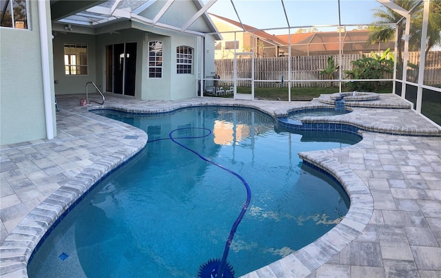 view of swimming pool with glass enclosure, a patio area, and an in ground hot tub