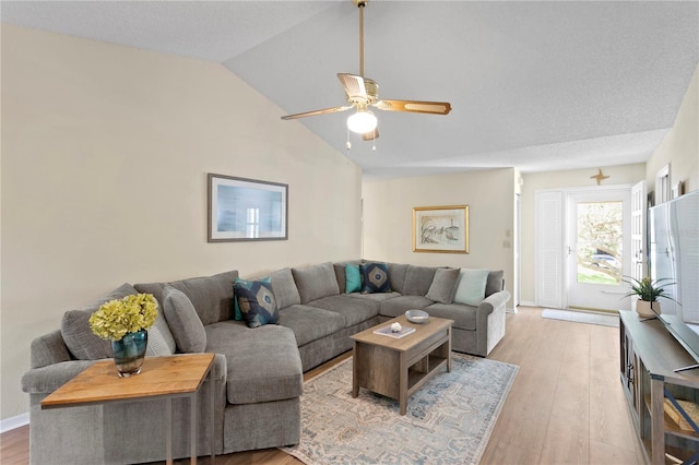 living room featuring ceiling fan, lofted ceiling, and light hardwood / wood-style flooring