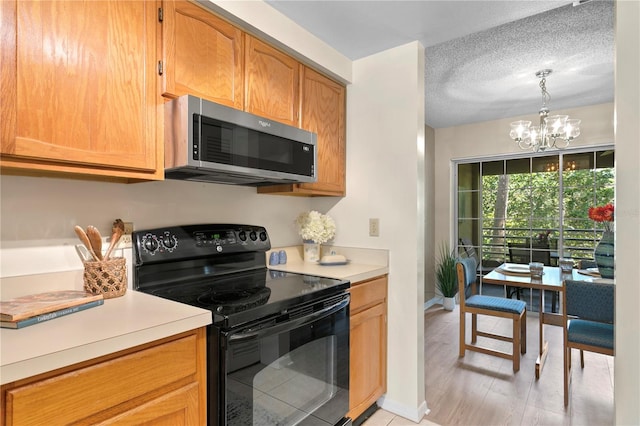 kitchen with an inviting chandelier, hanging light fixtures, electric range, light wood-type flooring, and a textured ceiling