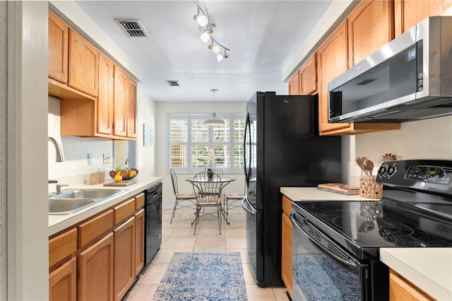 kitchen with track lighting, black appliances, sink, decorative light fixtures, and light tile patterned flooring