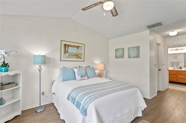 bedroom featuring ceiling fan, wood-type flooring, a textured ceiling, and connected bathroom