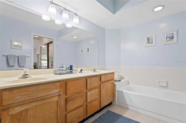 bathroom with tile patterned floors, a tub to relax in, and vanity