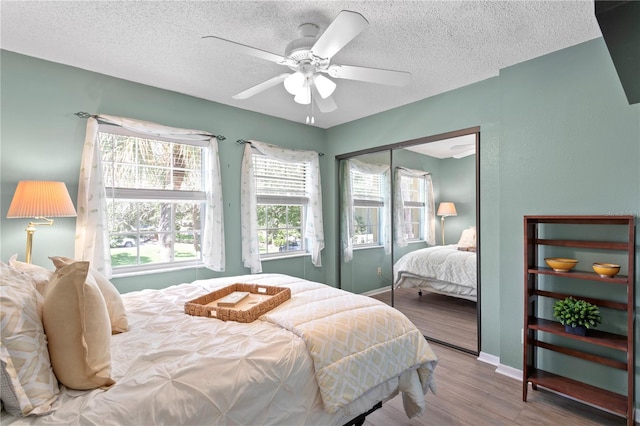 bedroom featuring wood-type flooring, a textured ceiling, a closet, and ceiling fan