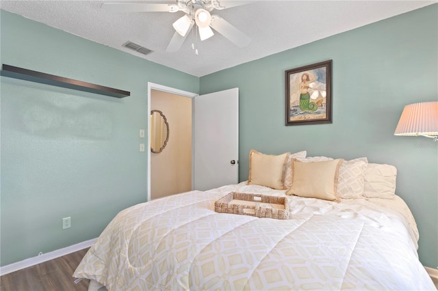 bedroom with hardwood / wood-style floors, ceiling fan, and a textured ceiling