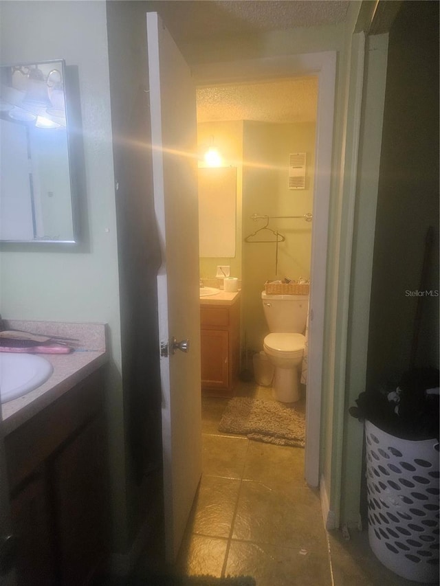 bathroom with toilet, vanity, and tile patterned floors