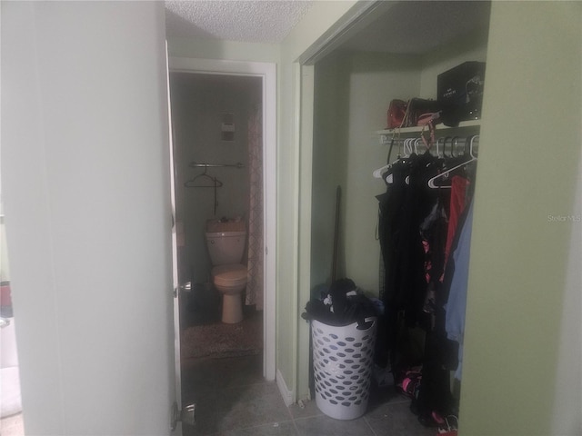 hallway with a textured ceiling and dark tile patterned floors